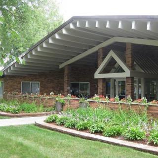 A modern brick house featuring an angled roof and well-maintained garden.
