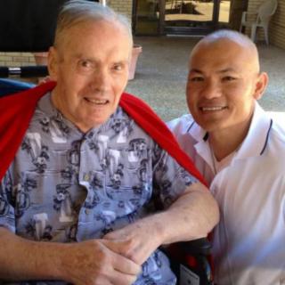 Two smiling individuals are posing together outdoors.