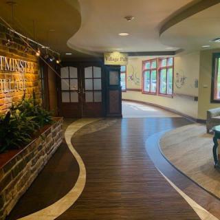A warmly lit hallway with a brick feature wall and curved wooden flooring.