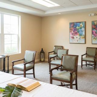 A small chapel with chairs, a table with an open book, and colorful artwork on the walls.