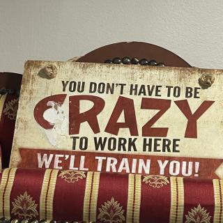 A humorous sign that reads, 'You don't have to be crazy to work here, we'll train you!'