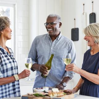 A group of friends enjoying wine and conversation in the kitchen.