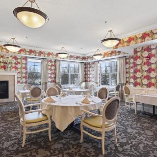 An elegant dining room with floral wallpaper and stylish seating arrangements.