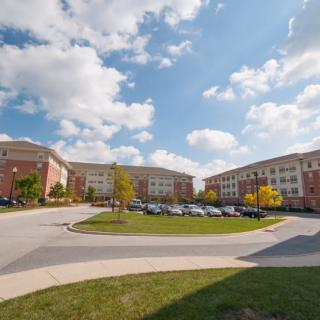 A sunny day view of a residential complex with multiple apartment buildings and a parking lot.