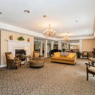 A spacious and elegantly decorated living room with chandeliers, a fireplace, and comfortable seating.