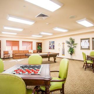 A spacious recreation room featuring a pool table and a puzzle setup, with comfortable seating and bright lighting.