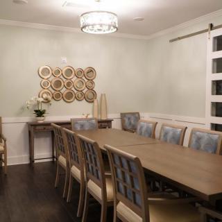 A modern dining room featuring a long table with multiple chairs, a chandelier above, and wall art for decoration.