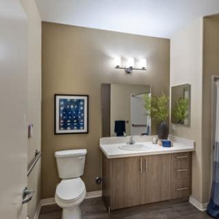 A modern bathroom with a vanity, mirror, and wall art.