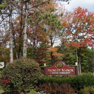 A scenic view of a sign surrounded by colorful autumn trees and lush greenery.