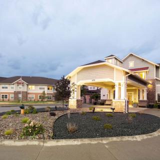 A well-lit residential building with landscaping at dusk.