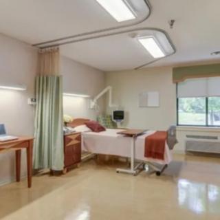 A clean and well-equipped hospital room with a bed and medical apparatus.