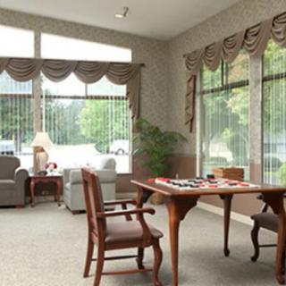 A bright living room with large windows, comfortable seating, and a wooden table.