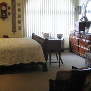 A cozy bedroom with antique furniture and soft lighting through vertical blinds.