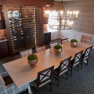 A stylish dining room featuring a long table with chairs, elegant chandelier, and decorative plants.