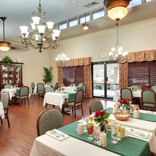A well-lit dining room with elegantly set tables and chandeliers.
