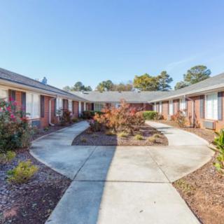 A courtyard surrounded by a residential building with a central sidewalk and landscaped areas.