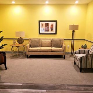 A cozy living room with yellow walls, featuring a sofa, decorative lamps, and artwork.