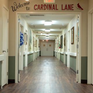 A well-lit hallway with 'Welcome to Cardinal Lane' signage, suggesting a cozy and inviting environment.