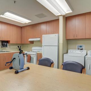 A functional and well-equipped kitchen and laundry area featuring a dining table with chairs, suitable for communal activities.