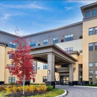 A modern residential building with a landscaped entrance and autumn foliage.