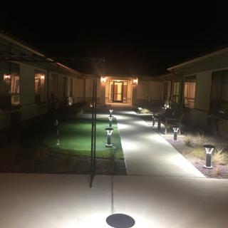 A well-lit pathway in a courtyard at night, surrounded by buildings.