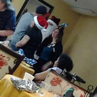 A group of people wearing Santa hats at a festive indoor gathering.