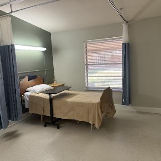 An empty hospital patient room with a bed and soft lighting.