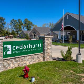 An assisted living facility with a prominent sign for Cedarhurst, surrounded by greenery on a sunny day.