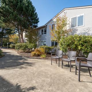 A peaceful outdoor area with chairs along a pathway next to a building surrounded by trees and greenery.