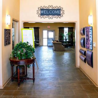 An inviting entrance hallway with a 'Welcome' sign, decorated with plants and artwork.