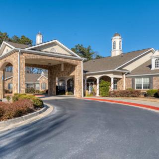 A residential building with a covered entrance and driveway under a clear blue sky.