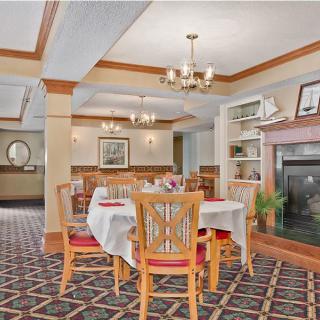 A cozy restaurant interior featuring a dining area with tables and chairs, a fireplace, and elegant chandeliers.