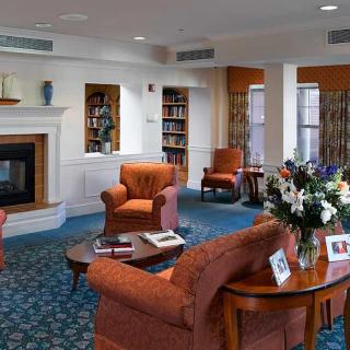 A cozy living room with armchairs, a fireplace, and bookshelves.
