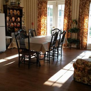 A sunlit dining room with a table and chairs, adorned with floral curtains.