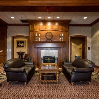 A luxurious lounge area featuring leather sofas, a fireplace, wood paneling, and elegant decor.