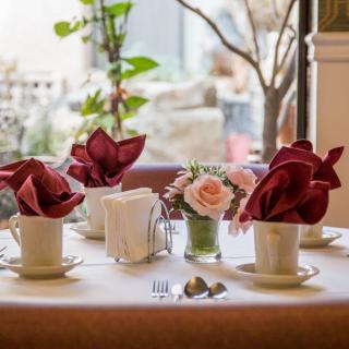 An elegantly set table with decorative napkins, flowers, and cups in a cozy restaurant environment.