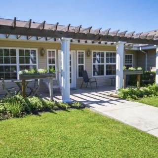 A cozy house with a pergola-covered patio and well-maintained lawn.
