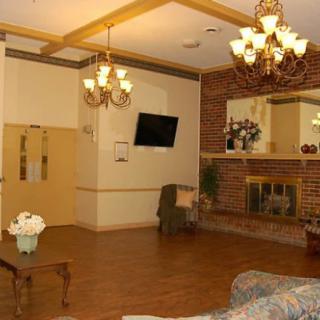 A cozy living room with a brick fireplace, chandeliers, and comfortable seating.