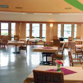 An empty dining area with neatly arranged tables and chairs, featuring large windows.