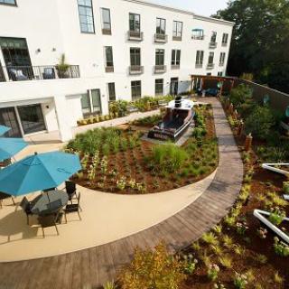 A beautifully landscaped garden with a winding pathway and outdoor seating adjacent to a modern building.