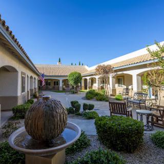 A serene courtyard featuring a central fountain, surrounded by lush greenery and comfortable seating, perfect for relaxation.