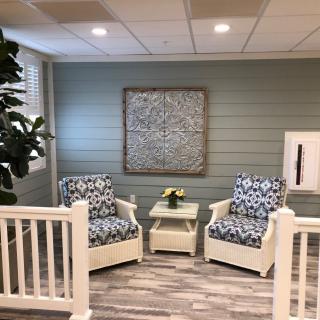 A cozy indoor seating area with two patterned armchairs, a small table, and decorative artwork on the wall.
