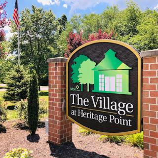 Entrance sign of The Village at Heritage Point, surrounded by lush greenery.