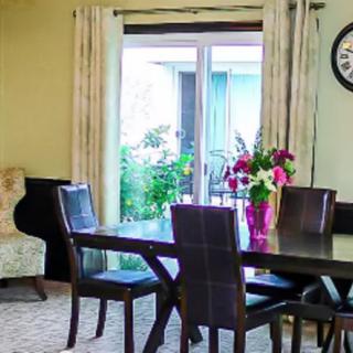 A cozy dining room featuring a table with chairs, adorned with a vase of flowers near a window.