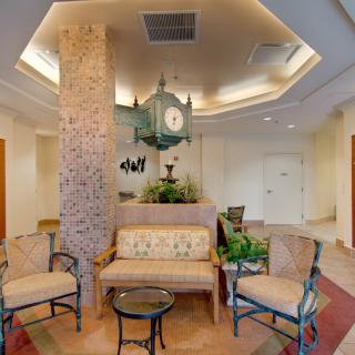 A cozy lobby seating area with elegant furniture, a central clock, and decorative plants.