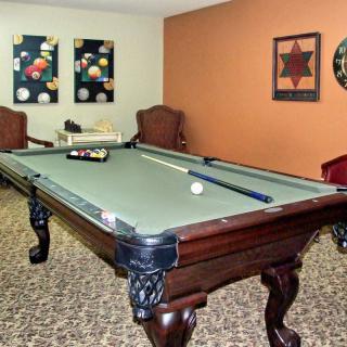 A game room featuring a billiards table with cue sticks and artwork on the walls.