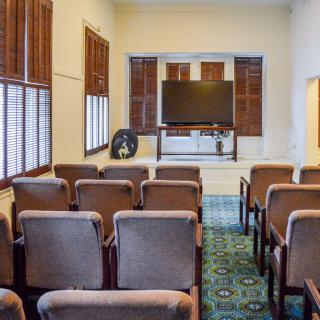 A small conference room with rows of chairs facing a large television.