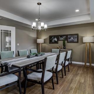 A modern dining room with a long table, chairs, and elegant lighting.