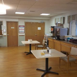 A clean and organized dining area within a healthcare facility, featuring tables and chairs arranged for meals.