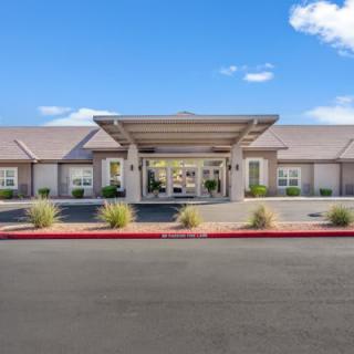 A modern building entrance with a clear blue sky and minimal landscaping.
